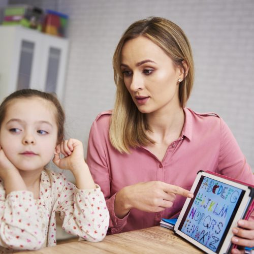 Bored girl and her mother studying with laptop at home